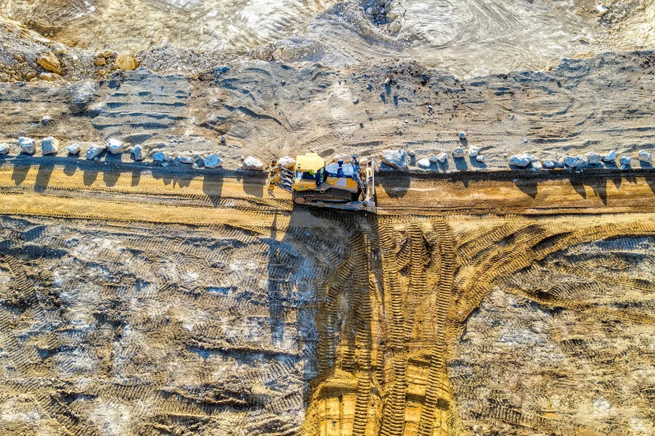 Aerial shot of bulldozer in action at a sandy construction site.
